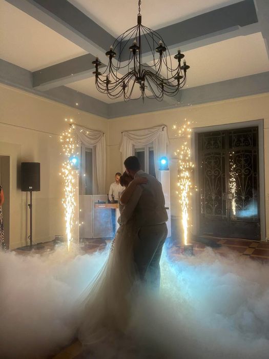 Newlyweds' first dance between two cold spark fountains, in the fog